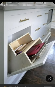 an open drawer on the side of a kitchen counter with papers and pencils in it