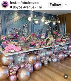 there is a long table with many balls on it and flowers in vases at the end