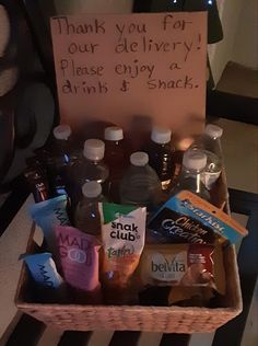 a wooden box filled with lots of food and drinks next to a sign that says thank you for our delivery please enjoy a drink