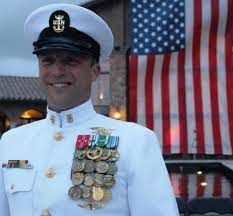 a man in uniform standing next to an american flag and a building with flags on it