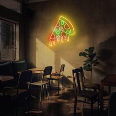 a neon pizza sign hanging on the side of a wall next to a dining room table