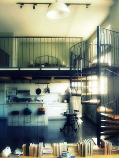 a spiral staircase in the middle of a room with books on the floor and stairs leading up to it