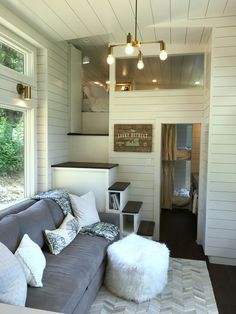 a living room filled with furniture next to a window covered in white blankets and pillows