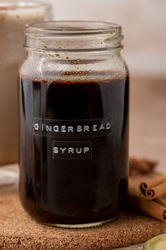 a glass jar filled with gingerbread syrup next to cinnamon sticks