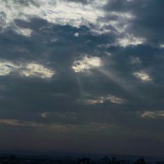 an airplane is flying in the sky with sun rays coming through the clouds above it