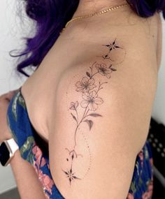 a woman with purple hair has a flower tattoo on her upper arm and shoulder area