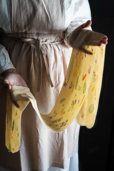 a person holding two bananas in their hands and wearing a yellow apron with designs on them