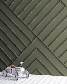 a small toy car sitting on top of a wooden floor in front of a wall