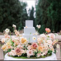 a wedding cake is surrounded by flowers and greenery