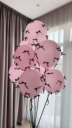 a bunch of pink balloons with black birds on them in front of a curtained window