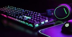 a keyboard, mouse and headphones lit up in the dark with neon lights on it