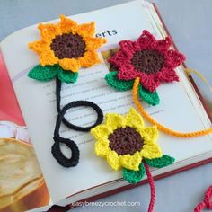 crocheted sunflowers are on top of an open book