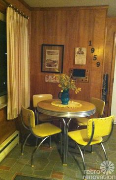 a dining room table with yellow chairs and a blue vase filled with flowers sitting on top of it