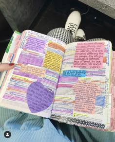 someone is holding an open bible in their hand and it has colorful writing on the pages