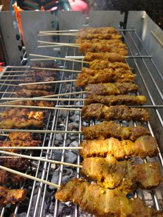 several skewers of food cooking on an outdoor grill