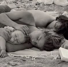 two women and a baby are laying on the beach