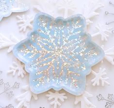 a snowflake made out of glass sitting on top of white snow flakes