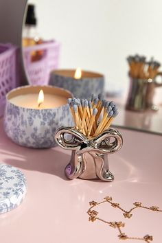 a pink table topped with candles and other decorative items next to a mirror on top of it