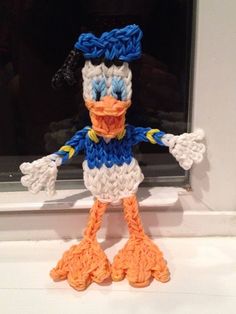 a crocheted ducky doll sitting in front of a black window sill