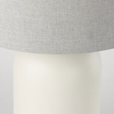 a white table lamp with a grey shade on it's top and bottom part