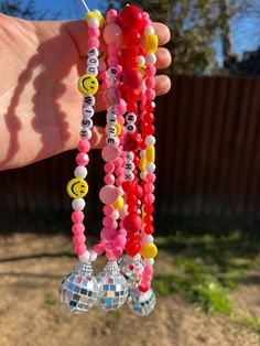 a person is holding up some colorful bracelets with smiley faces on them and disco balls hanging from the strings