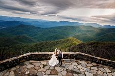 a bride and groom standing on top of a mountain