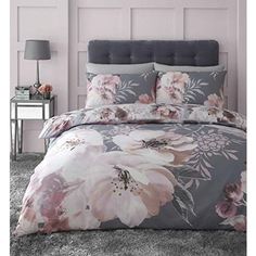 a bed with pink flowers and grey sheets