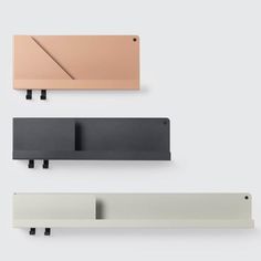 three different colored shelfs with hooks on the side and one is black, white, grey