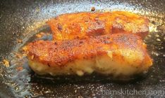 two pieces of meat cooking in a frying pan with oil on the top and bottom