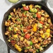 a skillet filled with meat and vegetables on top of a white napkin next to an avocado