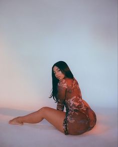 a woman is sitting on the floor in a red dress and posing with her legs crossed