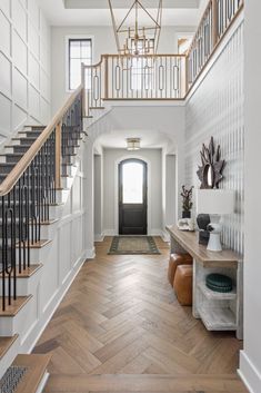 an entryway with wood floors and white walls, wooden stairs leading up to the second floor