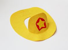 a yellow hat with a red star on the side and a circle shaped object in the middle