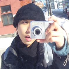 a person taking a photo with a camera in front of a building on a snowy street