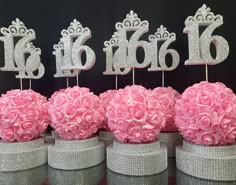 there are pink flowers and silver numbers on top of each other in the centerpieces