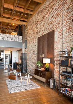 a living room filled with furniture next to a tall brick wall and wooden flooring