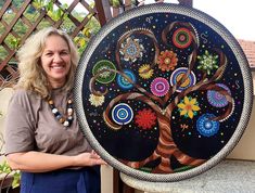 a woman standing next to a painted tree