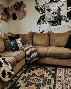 a living room with couches and rugs on the floor in front of a cow head wall