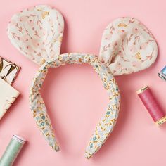 an assortment of sewing supplies laid out on a pink surface