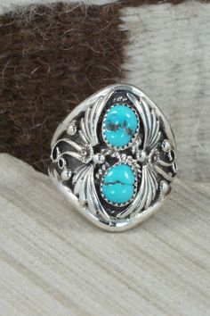 This Kingman turquoise and sterling silver ring was made by Navajo silversmith Calvin Belin. The inside is signed RB and stamped .925.Size: 14.25Length: 1 1/4"Width: 1 1/16"Free shipping on all orders! We ship with USPS and always include tracking. All orders ship within a day of payment.Returns are accepted up to 30 days after you receive your order. Just send us a message. Our shop offers cash back or store credit. The item must be returned in new condition. Sterling Silver Turquoise Ring With Concho, Sterling Silver Turquoise Rings With Concho Detail, Southwestern Turquoise Ring In Sterling Silver, Southwestern Sterling Silver Turquoise Ring For Anniversary, Sterling Silver Turquoise Concho Ring, Southwestern Turquoise Rings Stamped 925, Western Sterling Silver Turquoise Concho Ring, Western Turquoise Ring With Inlay, Western Style Turquoise Ring With Inlay