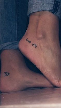 two people sitting on the floor with their feet crossed and one has a tattoo that reads, i love you