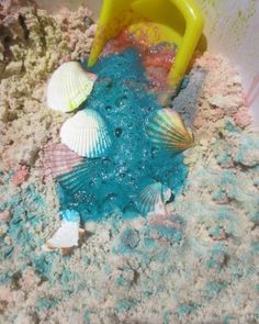 a bucket and some seashells in the sand