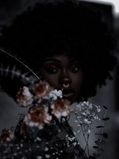 a woman with an afro holding flowers in her hand