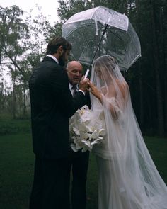 a bride and groom standing under an umbrella