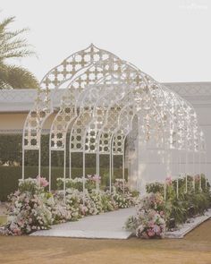 an outdoor wedding venue with flowers in the foreground and a pergolated walkway