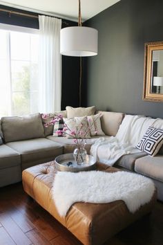 a living room filled with furniture and a large mirror on the wall above it's windows