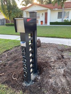 a mailbox sitting in the middle of a dirt patch next to a sidewalk and palm trees