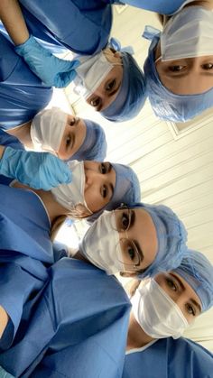 a group of doctors standing in a circle wearing scrubs and surgical garb on their heads