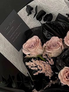 a bouquet of roses sitting on top of a table next to a black and white box