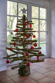 a christmas tree made out of branches with ornaments on it in front of a window